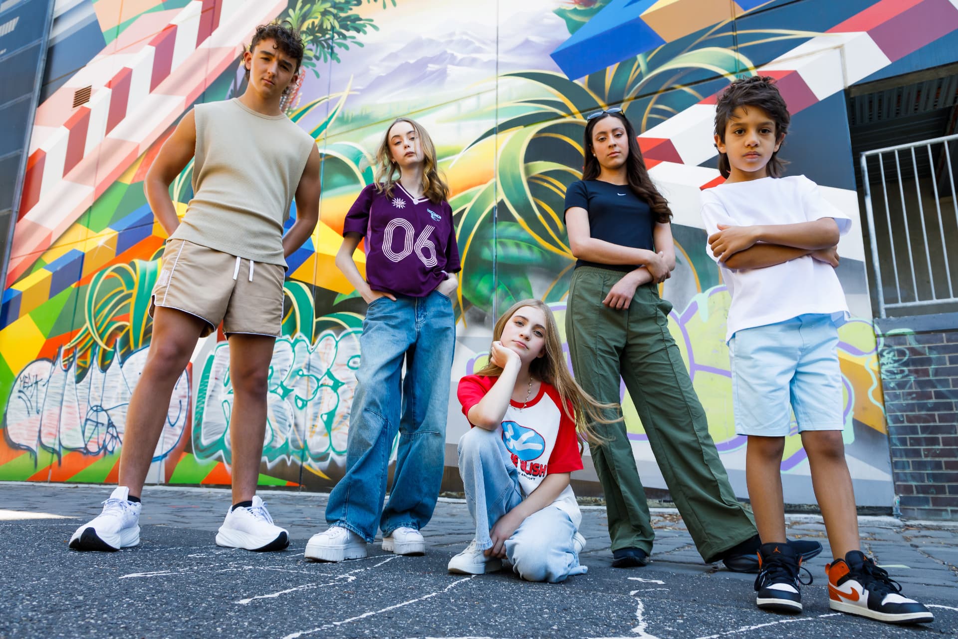 Group of young models posing in front of a colourful mural, photographed by POP! Photography